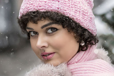 A stylish woman in pastel-colored warm clothes outdoors in the city in winter.snowfall,cold weather.