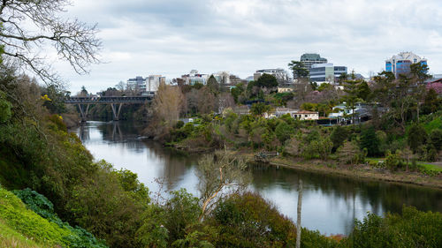 Arch bridge over river by buildings against sky