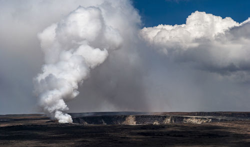 Smoke emitting from volcanic landscape against sky