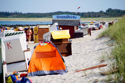 Hooded chairs on sand against sea at beach