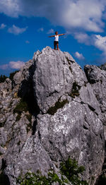 View of woman standing on rock against sky