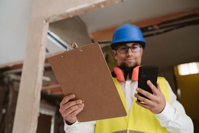 Foreman or architect working on mobile phone blueprints .construction site. home improvement