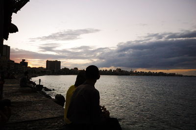 Rear view of silhouette man in sea against sky