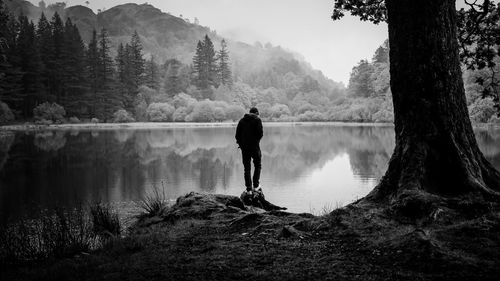 Rear view of man by lake against sky