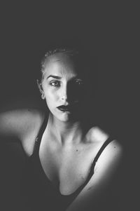 Close-up of young woman against black background