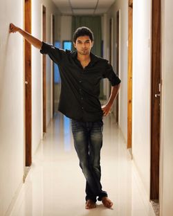 Full length portrait of young man standing in hotel corridor