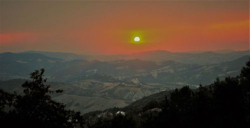 Scenic view of silhouette mountains against orange sky