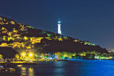 Illuminated buildings by sea at night