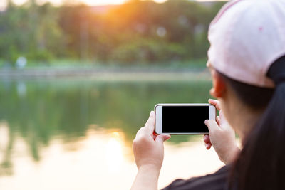 Midsection of man using mobile phone in lake