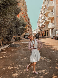 Full length of woman standing by building in city