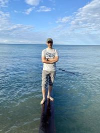 Full length of young man standing in sea against sky