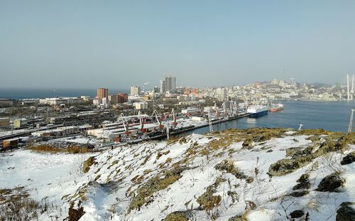 Aerial view of city by sea against clear sky