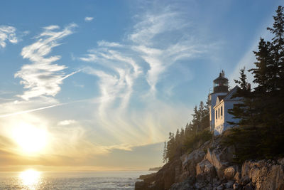 Lighthouse amidst sea and buildings against sky