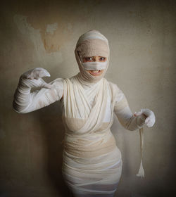 Portrait of woman wrapped with bandages against wall during halloween