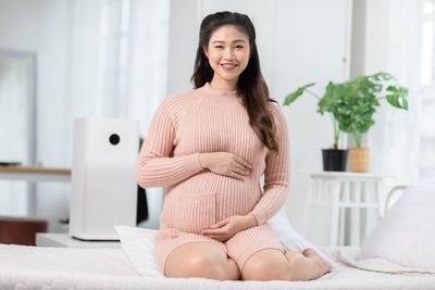 Portrait of smiling young woman sitting on bed