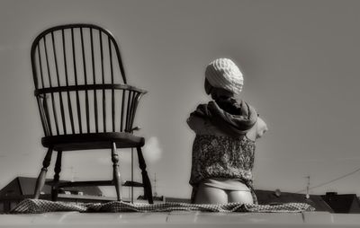 Rear view of woman sitting on chair against table