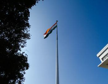 Low angle view of flag against clear blue sky