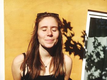 Portrait of smiling young woman against wall