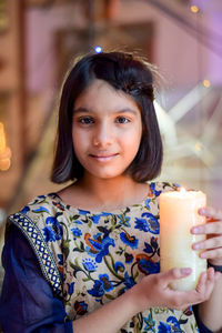 Portrait of girl holding lit candle during diwali