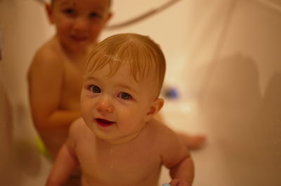 Cute little children having shower in bathtub