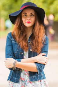 Portrait of beautiful woman in hat standing with arms crossed