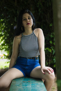 Portrait of beautiful young woman sitting on bench