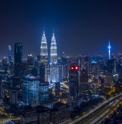 Illuminated buildings in city at night against sky