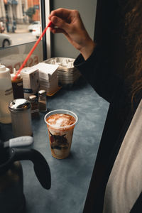 Midsection of woman holding coffee cup on table at cafe