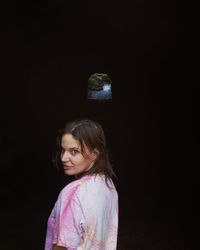 Portrait of a girl standing against black background