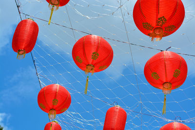 Low angle view of lanterns hanging against blue sky