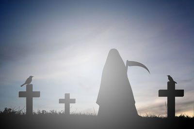 Cross in cemetery against sky