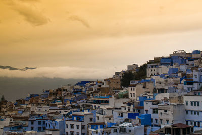 Buildings in city against sky during sunset