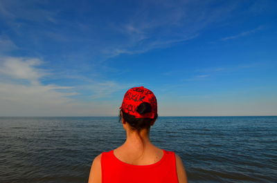 Rear view of woman standing by sea against sky