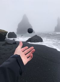 Cropped hand catching rock at beach