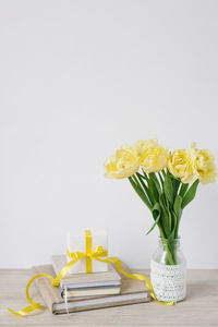 A gift box with a bow in the workplace with bouquets of bright yellow flowers and a stack