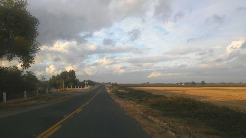 Country road against cloudy sky