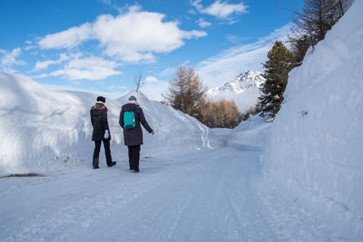 Rear view of friends walking on snow covered landscape