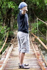 Full length of man standing on footbridge in forest