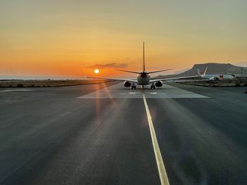 Car on airport runway against sky during sunset