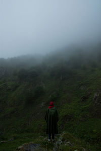 Rear view of woman walking on mountain against sky