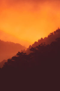 Scenic view of silhouette mountains against orange sky