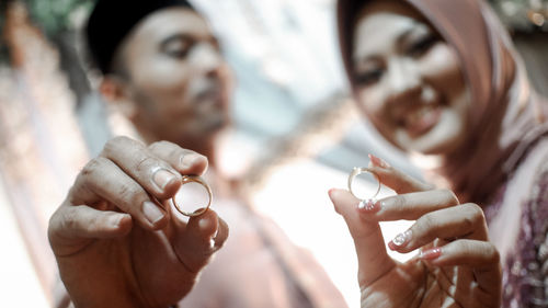 Close-up portrait of couple holding wedding rings