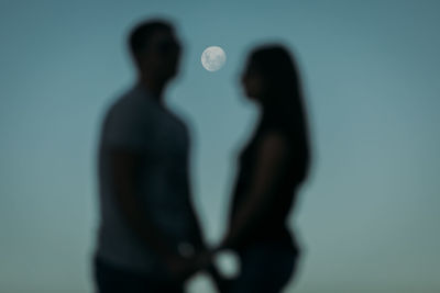 Silhouette of man and woman standing against blue background