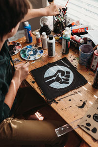 Teen boy painting black lives matter symbol on a protest sign.