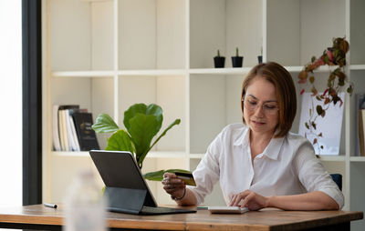 Young woman using phone while sitting on table