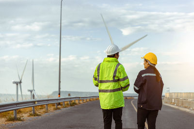 Rear view of engineer examining windmill