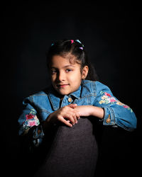 Portrait of boy looking away while standing against black background