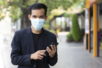 Portrait of young man using mobile phone in city