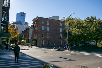 People walking on city street by buildings against sky