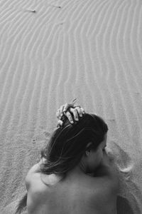 Rear view of young woman relaxing on sand